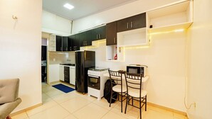A compact kitchen with a dining area, featuring a stove, microwave, and cabinets.