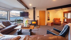 A cozy living room with a fireplace, leather furniture, and a large window overlooking a scenic view.