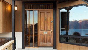 A wooden front door with a glass panel, a mailbox, and a view of mountains through the window.