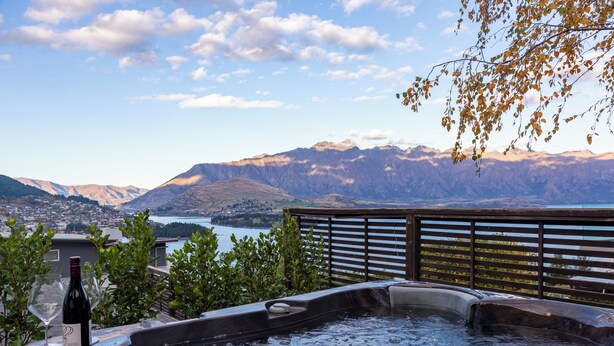A hot tub with a view of mountains and a lake.