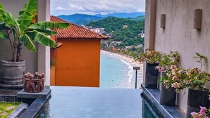 A pool area with clear water, surrounded by potted plants and a view of a beach and mountains in the distance. - PISCIS CONDO
Dawn overlooking the most beautiful bay in Mexico. (Zihuatanejo)