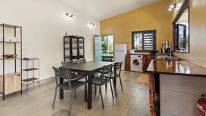 Una cocina compacta con comedor, lavadora y un ventanal con vistas a la vegetación.