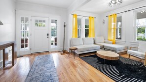 Un salón amplio con un sofá modular, una mesa de centro redonda y una alfombra azul estampada.