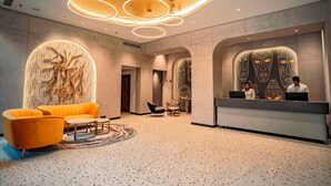 A lobby with a reception desk, a sofa, and a patterned wall. - Welina Hotel  (Bhubaneshwar)