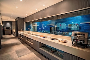 Una cocina moderna con una encimera amplia, un tostador y vistas de la ciudad a través de un ventanal grande.