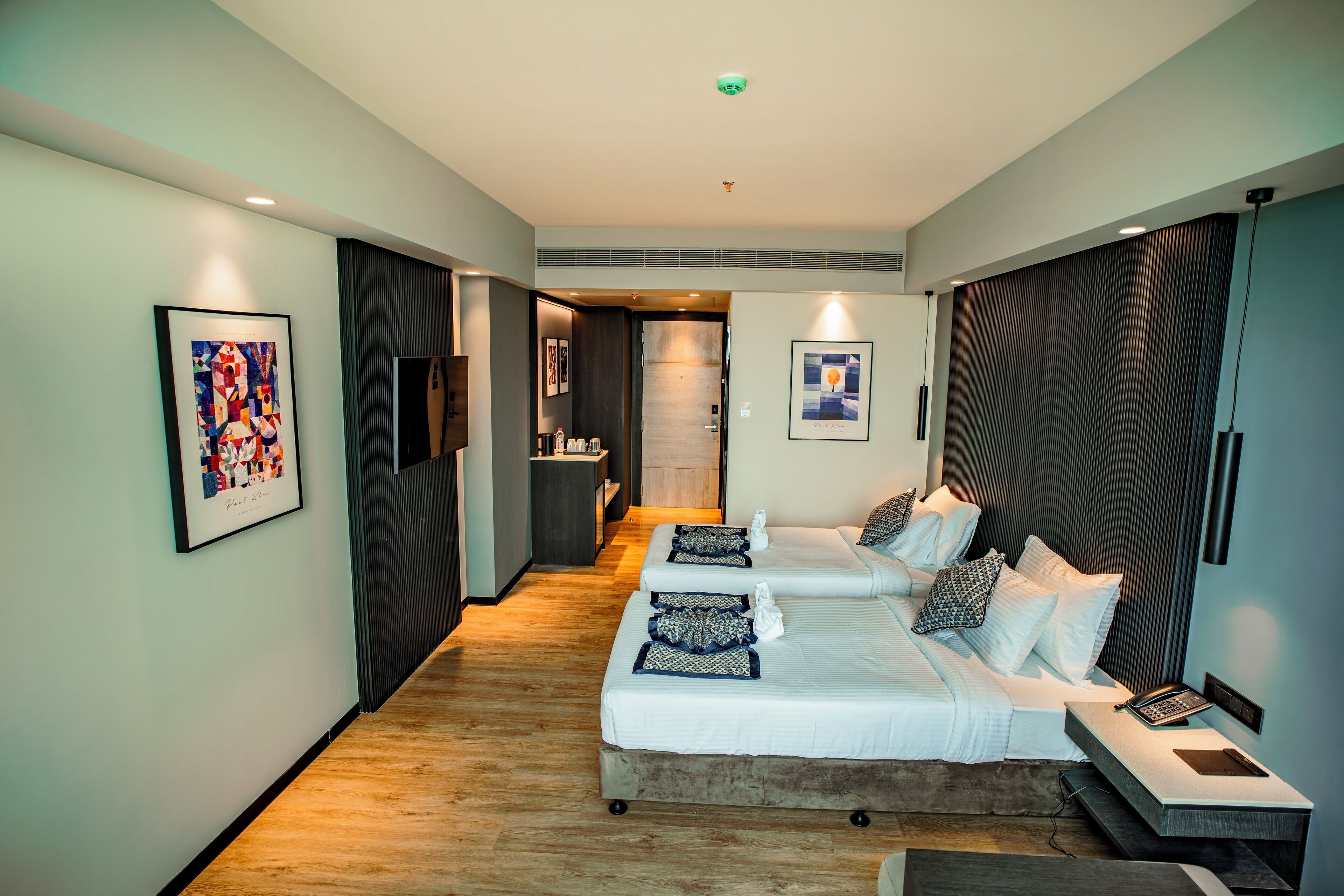 Una habitación de hotel moderna con una cama grande, una mesita de noche con teléfono y un pequeño rincón de descanso.