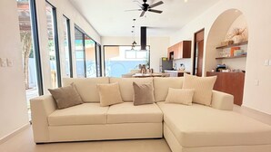 A modern living room with a sectional sofa, a wooden coffee table, and a ceiling fan.