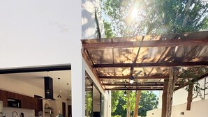A modern outdoor pool area with a covered seating area and a kitchen visible through an open door.