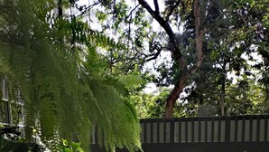 A patio area with artificial grass, white plastic chairs, and potted plants. - Ella Way Resort-Kandy (Hindagala)