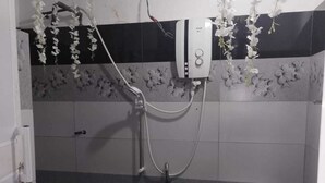 Baño con ducha, inodoro y calentador mural.