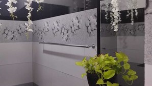 Un baño con inodoro, lavabo con espejo y zona de ducha.