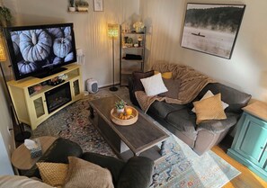 Una sala de estar acogedora con televisión, sofá y mesa de centro.