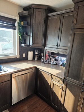 Una cocina con alacenas de madera oscura, lavavajillas y ventana con vistas.