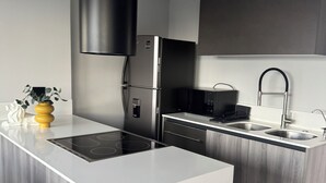 A modern kitchen with a central island, stainless steel appliances, and a black range hood.