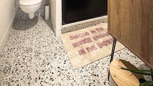 Un baño pequeño con ducha, inodoro y tocador de madera.