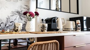 Una cocina moderna con cafetera, tetera y tazas sobre la encimera.