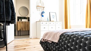 Un dormitorio con cama, cómoda, espejo y ventana con cortinas.