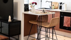 Una cocina moderna con comedor, piso de madera y un televisor sobre un soporte negro.