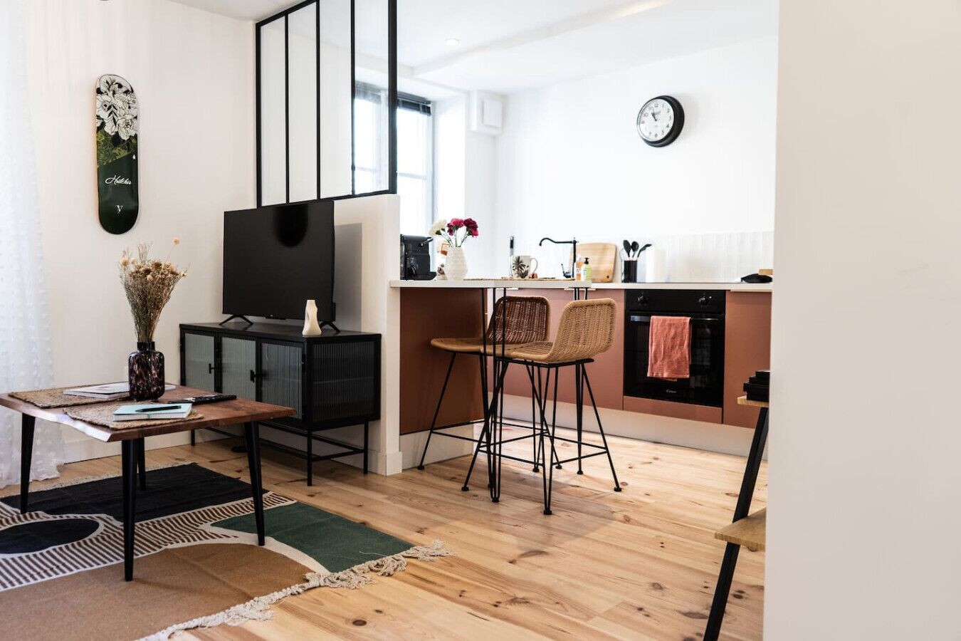 Una cocina moderna con un mueble de TV negro, suelo de madera y una zona de comedor con dos sillas.