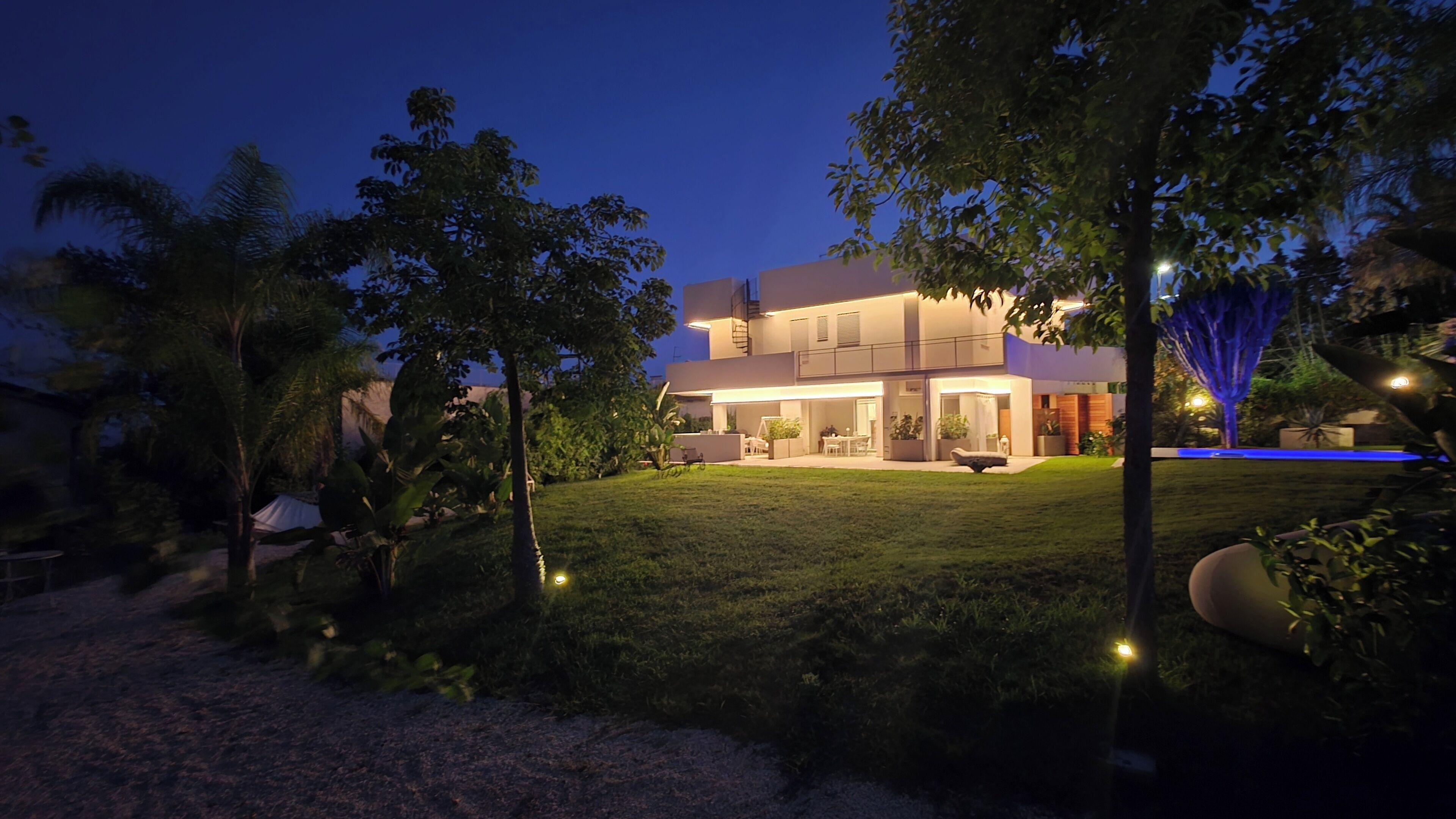 A modern two-story house with a well-maintained lawn and a swimming pool.