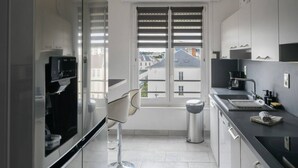 Una cocina moderna con ventana, una cafetera y un cubo de basura.