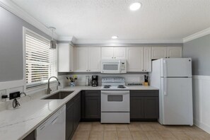 A kitchen with white cabinets, a microwave, a stove, and a refrigerator.