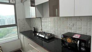 A modern kitchen with white cabinets, a black countertop, and a gas stove.