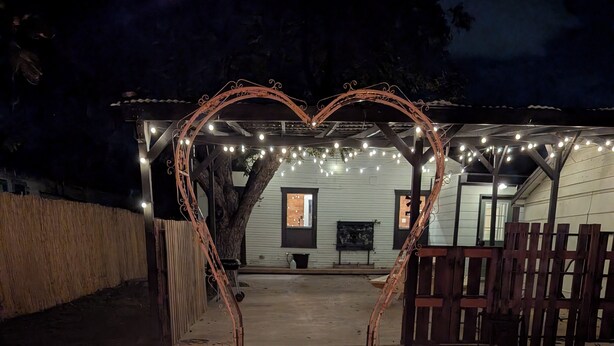 A heart-shaped archway with string lights, a fire pit, and a wooden fence.