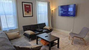 A modern living room with a sofa, a coffee table, a TV, and a lamp.