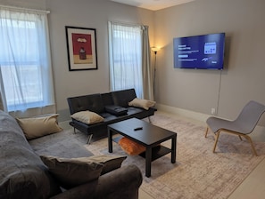 Un salon moderne avec un canapé, une table basse, un téléviseur et une lampe.