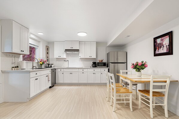 Una cocina moderna con armarios blancos, una mesa de comedor de madera y sillas.