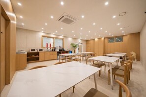 A modern dining area with tables and chairs, a kitchen area with appliances, and a large window. - Incheon BrownDot Hotel Guwol (Incheon)