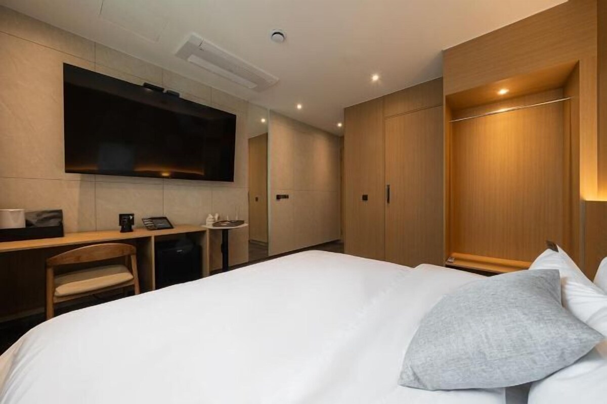 Une chambre d’hôtel équipée d’un lit, d’un bureau, d’un téléviseur fixé au mur et d’une armoire.