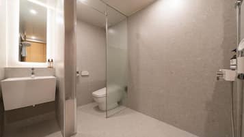 A modern bathroom with a glass shower enclosure, a white sink, and a toilet.
