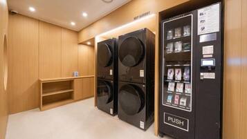 A laundry facility with two large washers and dryers, a vending machine, and a wooden bench.
