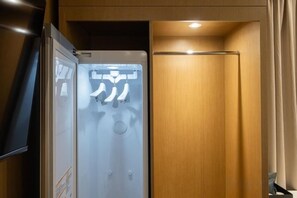A hotel room with a minibar, a flat-screen TV, and a wooden door.