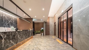 A modern reception area with a marble counter, a seating area, and a hallway leading to elevators. - Incheon BrownDot Hotel Guwol (Incheon)