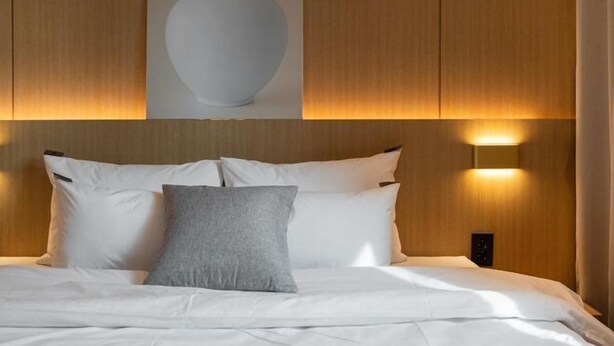 A neatly made bed with white and gray pillows, a wall-mounted light, and a framed picture above the bed. - Incheon BrownDot Hotel Guwol (Incheon)