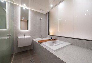 Une salle de bain moderne avec une grande baignoire, un lavabo et une douche à l’italienne.