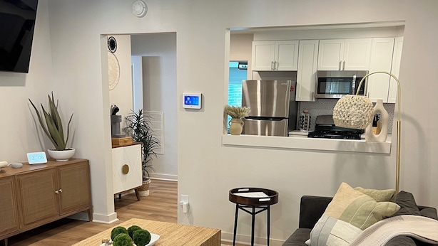 Un salon moderne avec un canapé, une table basse et un coin cuisine à l’arrière-plan.