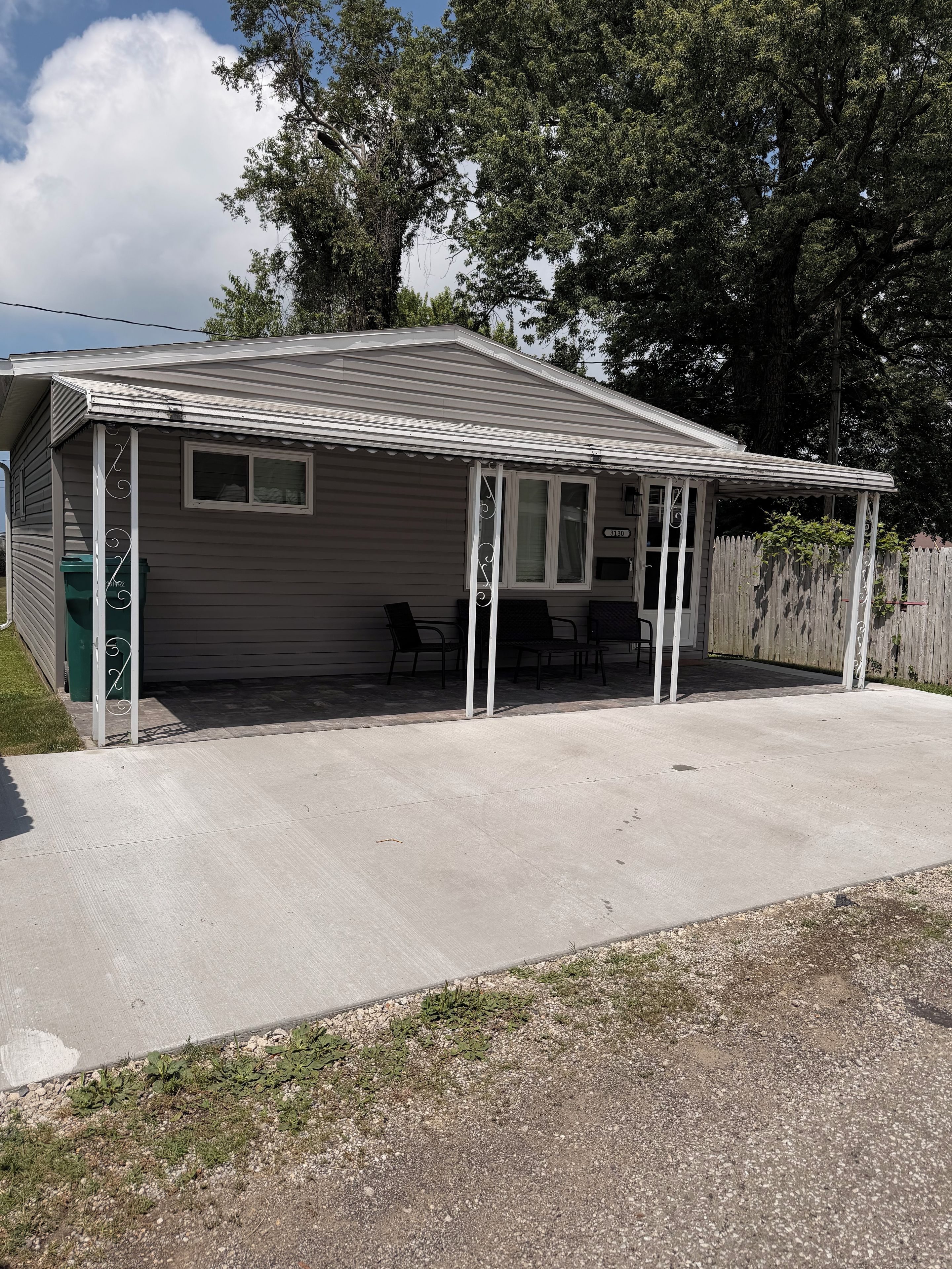 A single-story house with a covered patio area, a fenced yard, and a mailbox.