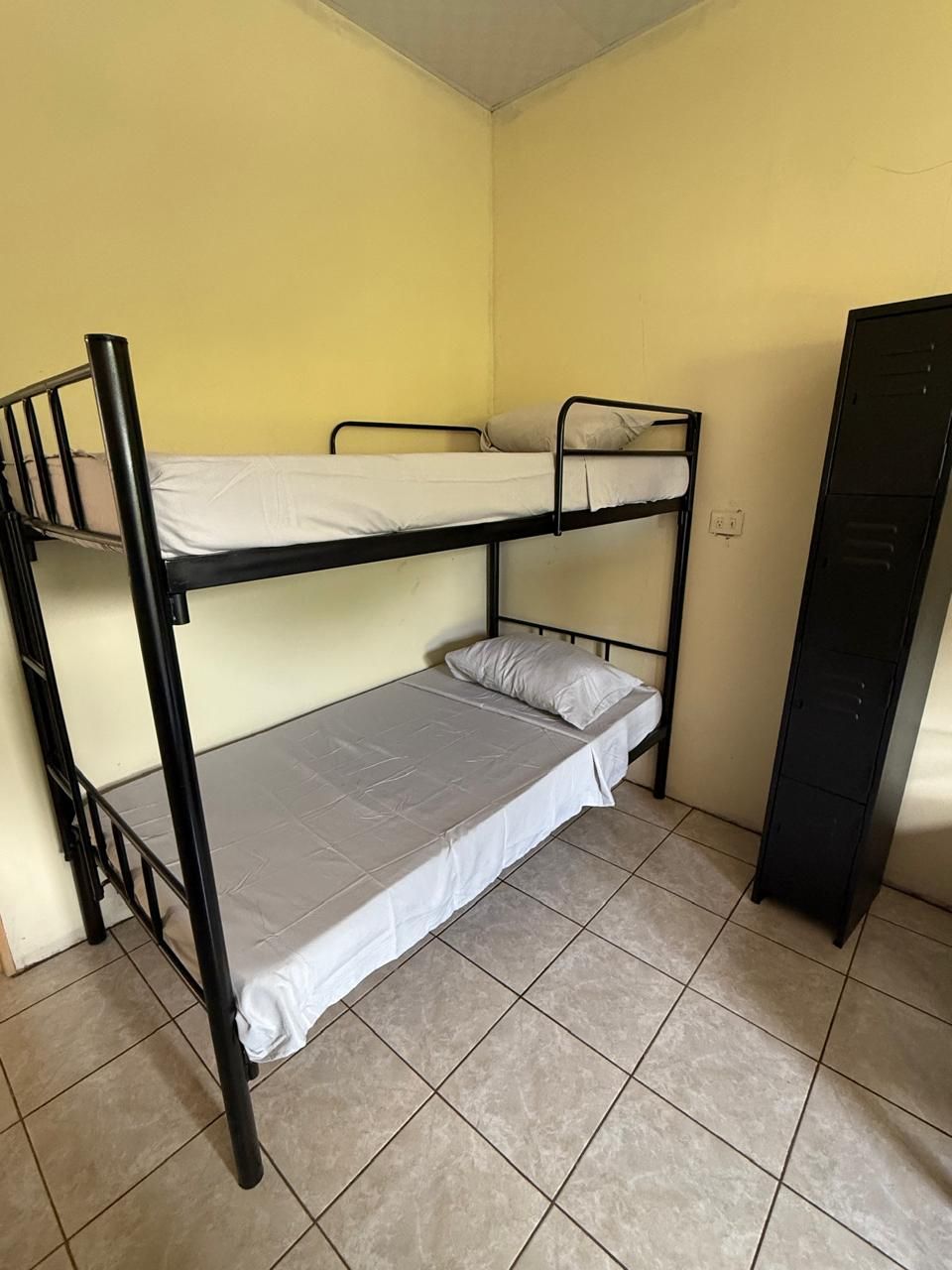 A bunk bed room with a tiled floor and a black wardrobe.