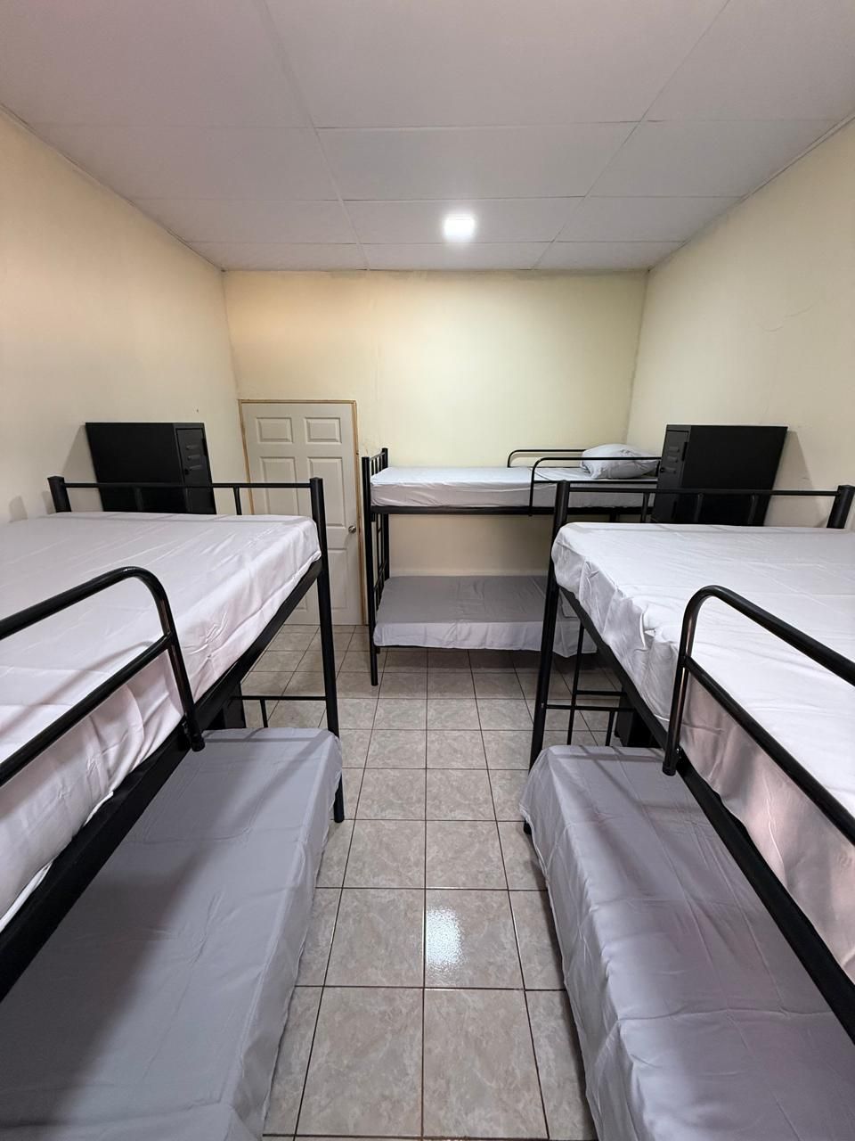 A dormitory room with four bunk beds, a desk, and a chair.