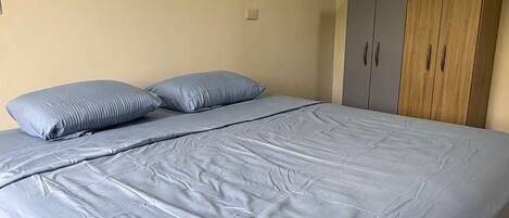 A bedroom with a bed, two pillows, and a wardrobe.