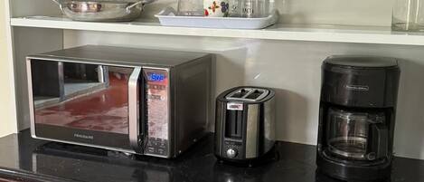 A kitchen with a microwave, toaster, and coffee maker on the counter.