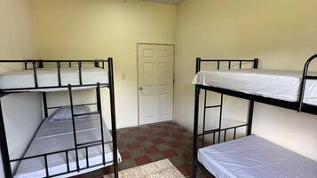 Un dormitorio con dos literas, piso de baldosas y una puerta.