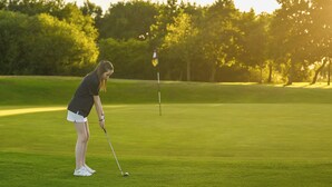 A person on a golf course with a flagstick in the distance. - Luxury lodges with views of Lancashire rolling hills & our beautiful golf course (Staining)