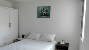 A bedroom with a bed, white curtains, a nightstand, a cabinet, and a painting on the wall. - Comfortable apartment south cali - valle de lilí with nature view (Cali)