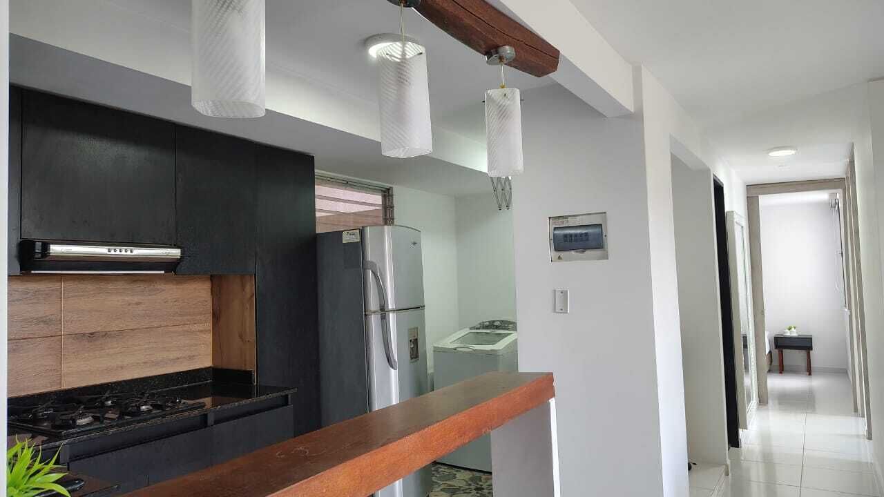 A modern kitchen with dark cabinetry, a stainless steel refrigerator, and a wooden countertop.