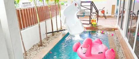A swimming pool with a slide and inflatable toys.